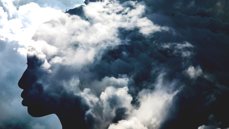 This conceptual image shows a profile of a person emerging from a dreamlike area of clouds.